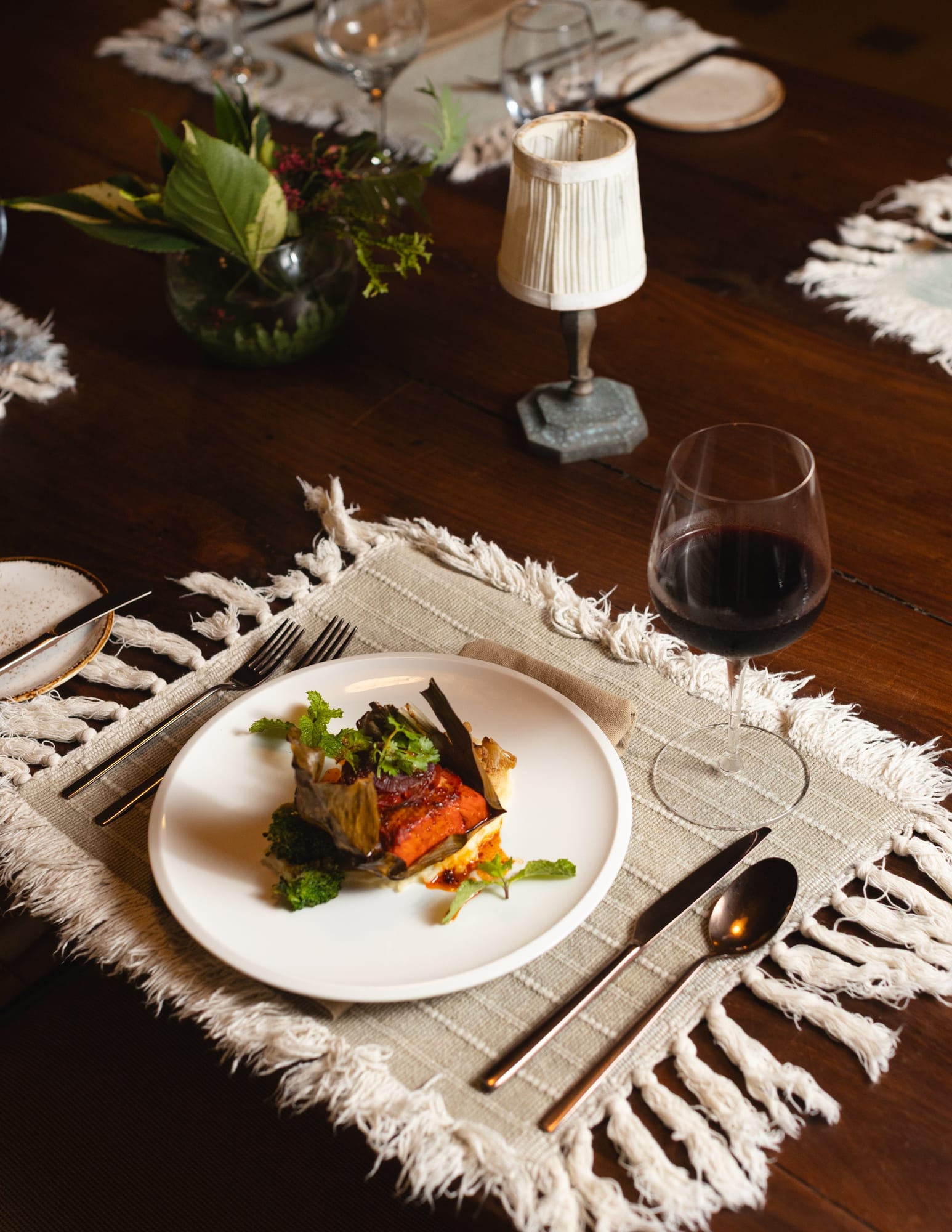 A wooden table on Placencia beach set with grilled snapper, coconut rice, fresh ceviche, and a chilled cocktail at golden hour